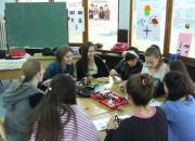 Girls sitting around a table making robots from Lego parts.