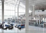 Inside the Qatar National Library, showing book shelves, seating and good light from floor to ceiling windows and skylights.