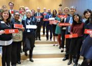 Group photo of 19 representatives from library, archive, museum and education sectors at SCCR/37. They are standing in a long line down a shallow stairs in the WIPO conference hall, holding organization name plaques.