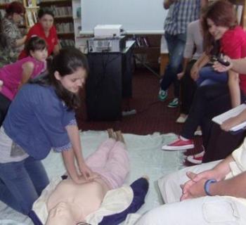Children and adults practising first aid on a first aid dummy.