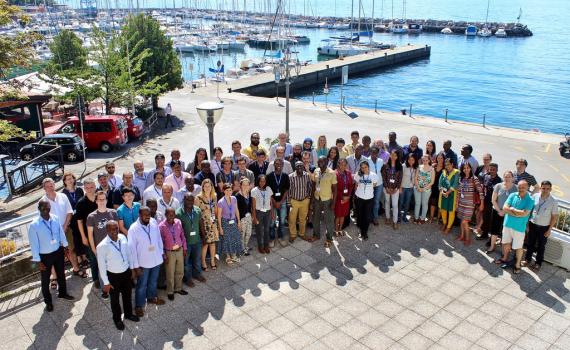 A large group of people, smiling, near the sea in Trieste. 