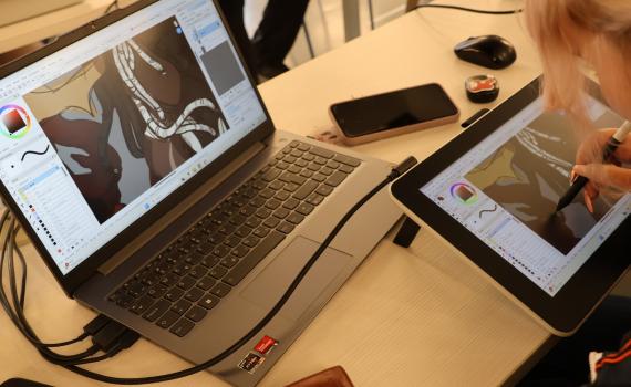 A young person using a graphic tablet for drawing.