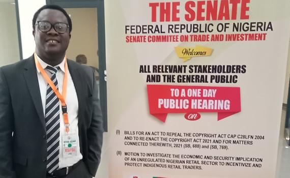 Desmond Oriakhogba next to a poster advertising the Senate hearing.