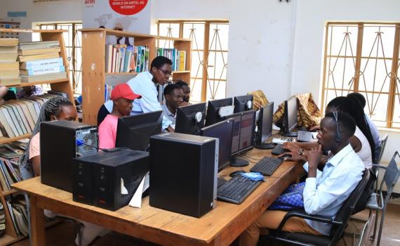 Librarian training people to use desktop computers in Mbarara Public Liibrary.