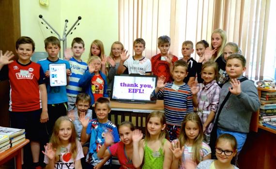 Children at Pelči Library (Latvia) celebrate the arrival of new equipment bought with the EIFL prize money - a touch screen computer monitor and a tablet e-book reader.