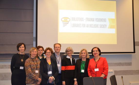 Group of delegates in front of screen with name of conference